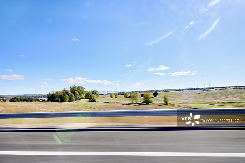 模糊的侧视图，透过汽车窗户看到的田野与蓝天图片素材