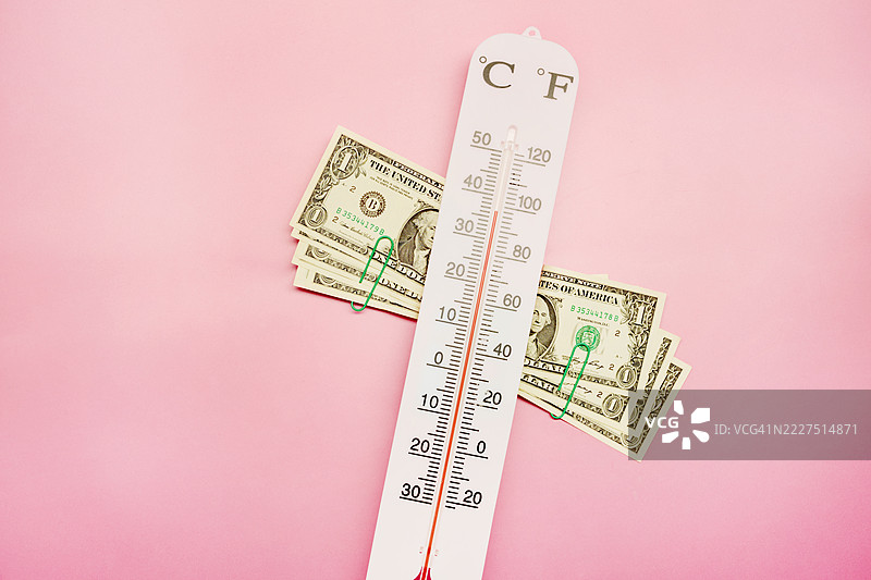 粉色背景上的温度计和美元钞票图片素材