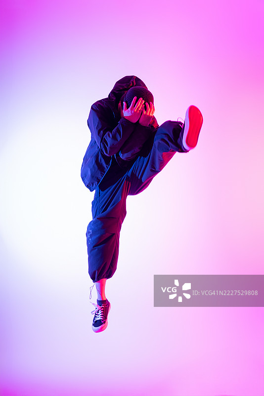 年轻亚洲男子在灯光效果下动态跳跃的肖像。图片素材