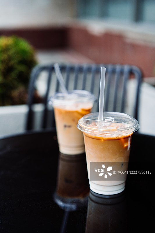 户外黑色桌子上的清澈杯子里的清爽冰拿铁图片素材
