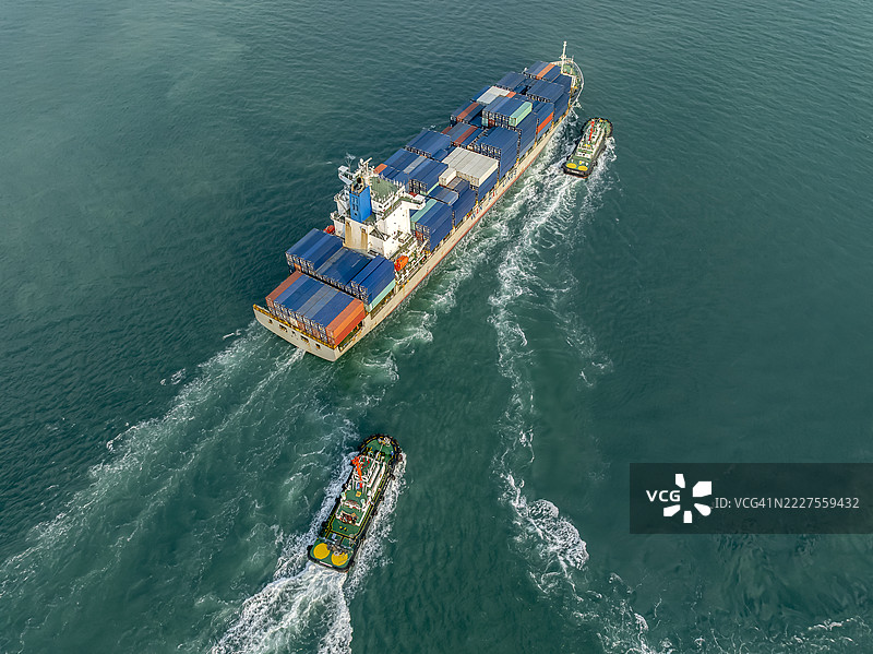 航拍视角，拖船将大型集装箱船推入港口，全球商业进出口及运输。图片素材