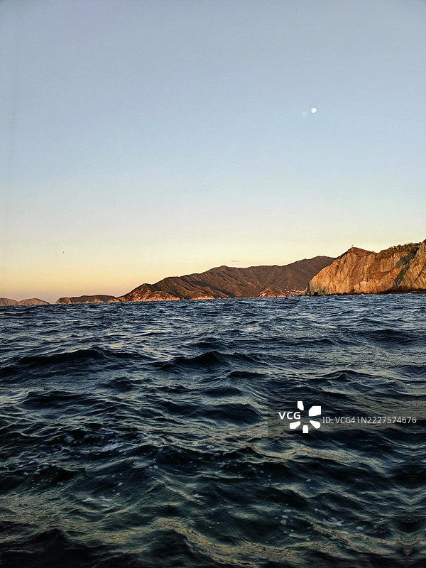 日落时分，背景是山脉的波涛汹涌的水域，哥伦比亚马格达莱纳省圣玛尔塔。图片素材