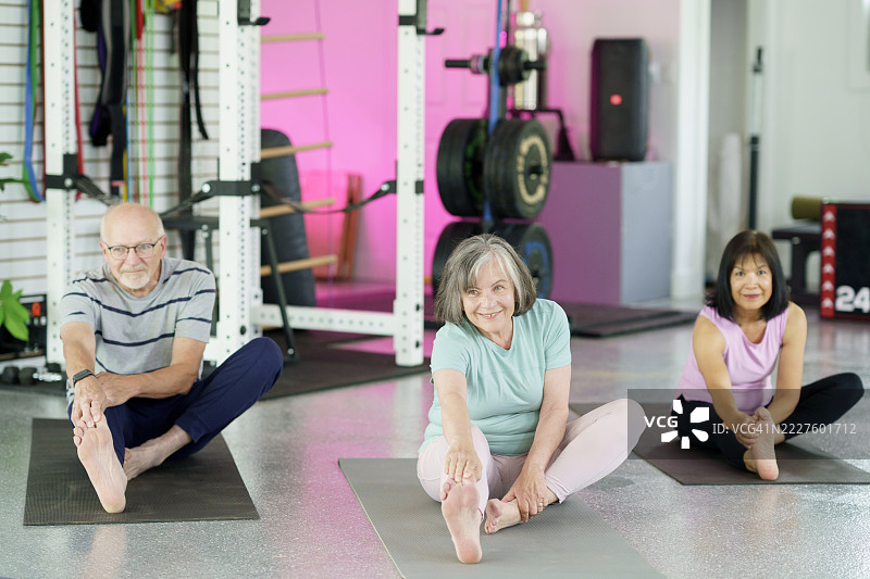 老年人在现代健身工作室练习温和的坐姿瑜伽拉伸图片素材