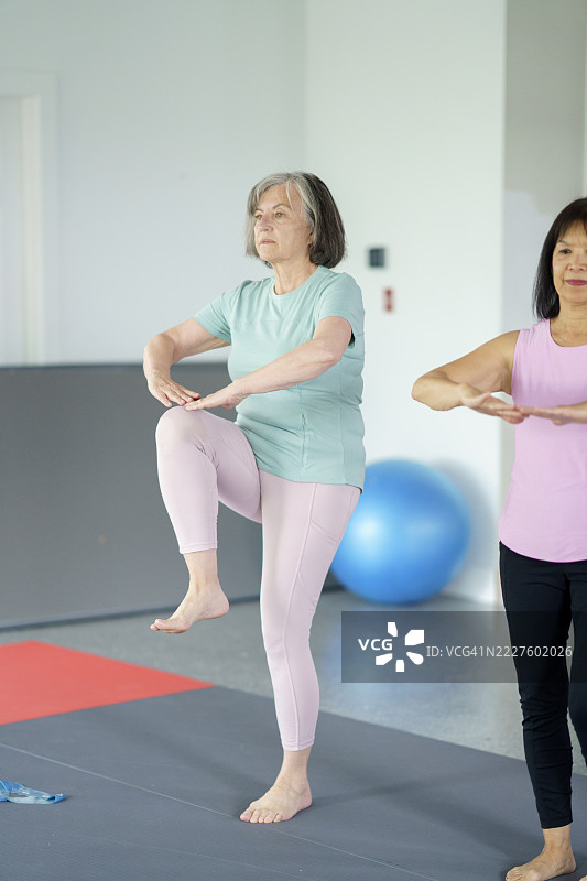 老年女性在明亮的瑜伽室中练习瑜伽以增强健康和平衡图片素材