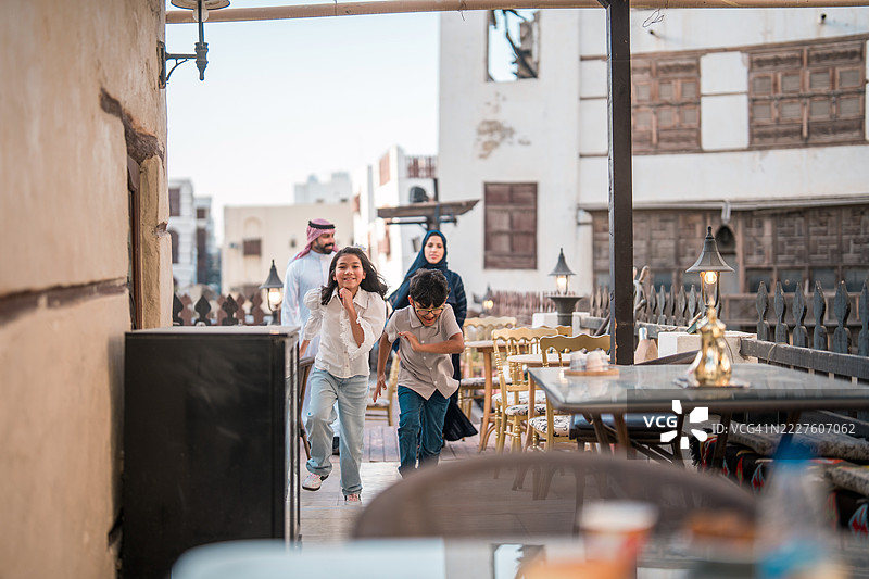 微笑的阿拉伯家庭抵达历史悠久的阿尔巴拉德区户外餐厅图片素材