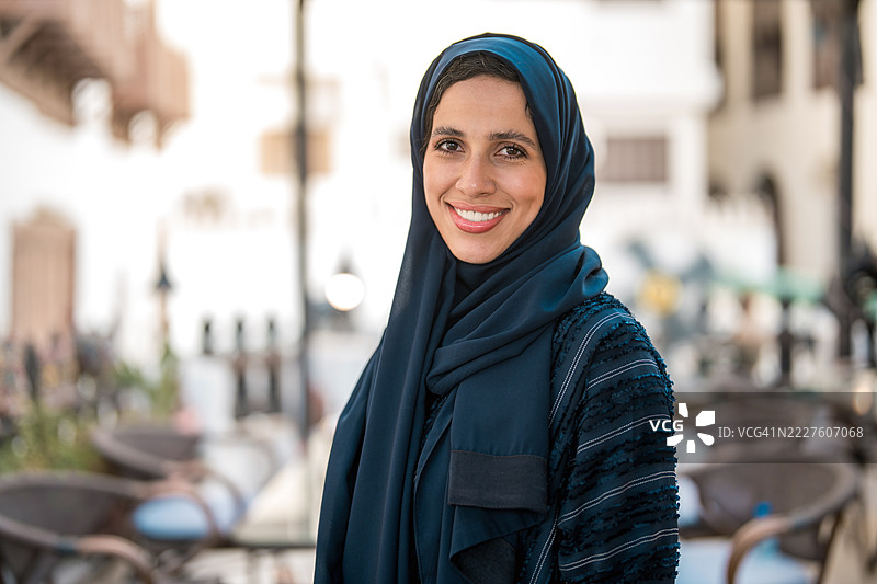在阿尔巴拉德的户外，微笑的阿拉伯女性在柔和的自然光下。图片素材