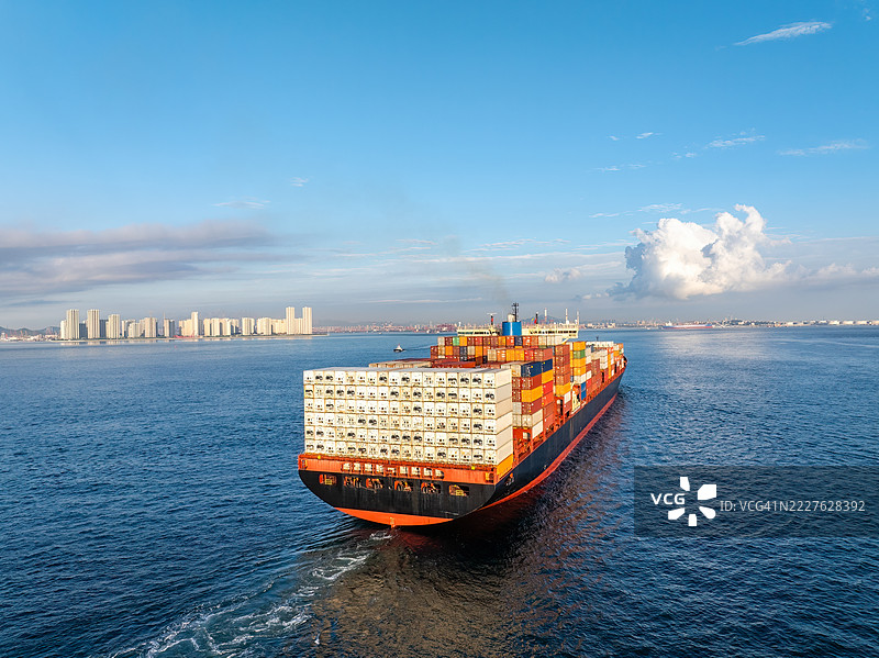 无人机视角下的集装箱船在青岛城市天际线前航行图片素材