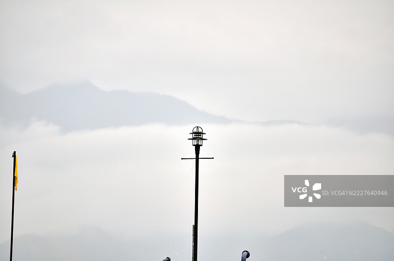 一根高大的灯柱上方有一个分层的灯笼，背景是朦胧的天空。图片素材