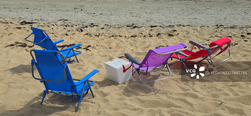 三把沙滩椅，中间放着一个白色的冰箱。图片素材