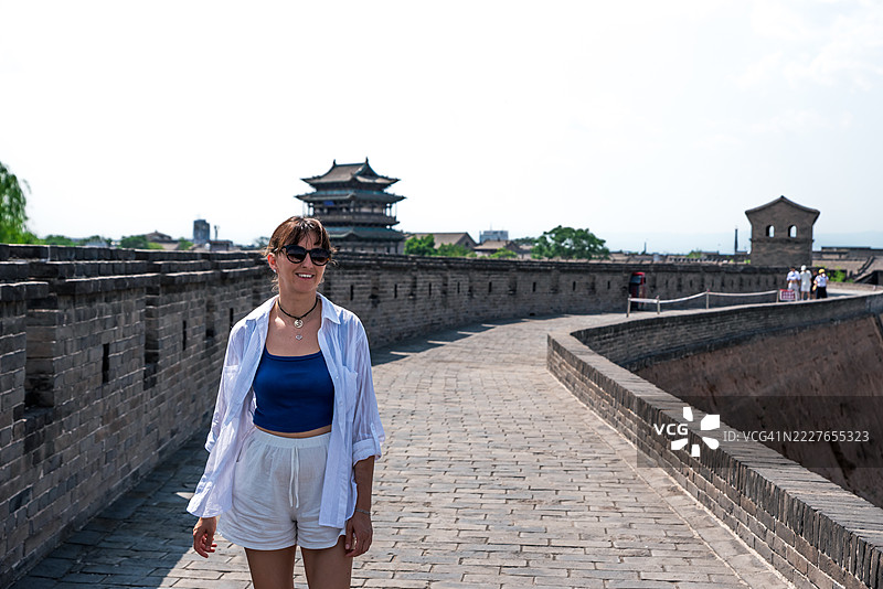 年轻女性在阳光明媚的日子里享受在平遥城墙上的散步。图片素材