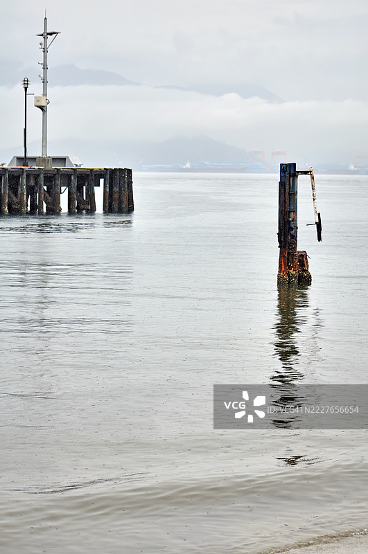 一个宁静的码头延伸至平静的水面，天空布满云彩。图片素材