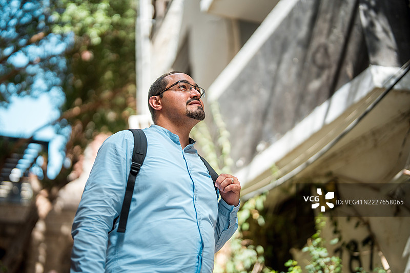 中年阿拉伯男性穿着浅蓝色衬衫，探索历史悠久的阿尔巴拉德街道图片素材