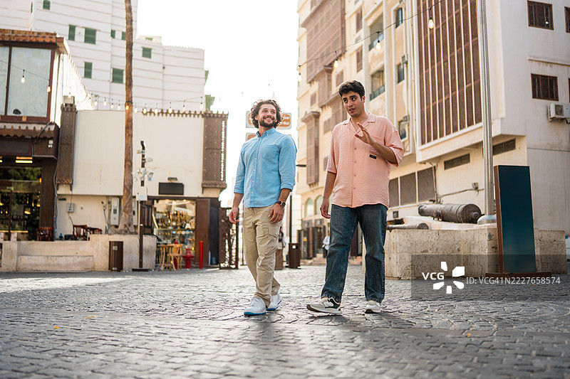 中年男子在沙特阿拉伯的历史悠久的阿尔巴拉德区的鹅卵石街道上漫步图片素材