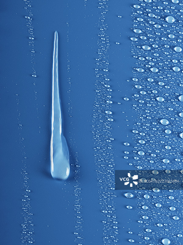 水滴沿着湿润的蓝色表面滑落。图片素材