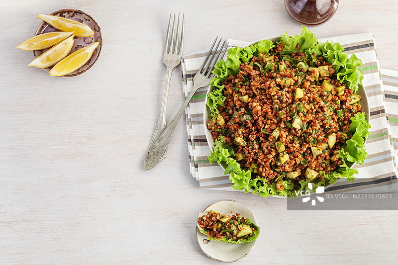 荞麦沙拉。荞麦基西尔。白色碗中盛着煮熟的荞麦和生菜，背景为白色。健康的自制素食。荞麦塔布勒沙拉。传统的中东或阿拉伯菜肴。黎凡特素食沙拉。图片素材