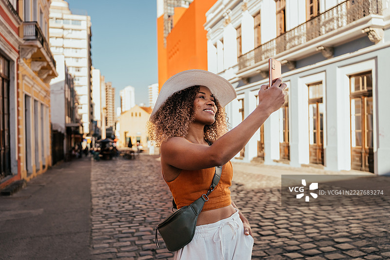 年轻游客在城市里用智能手机自拍图片素材