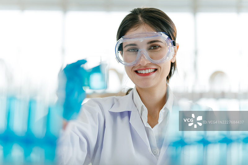实验室中微笑着面对镜头的友好女性科学家的特写肖像。图片素材