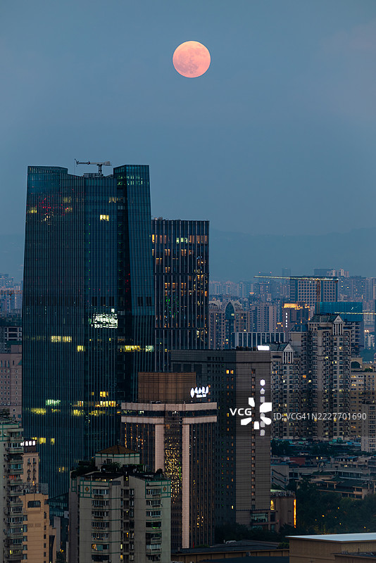 黄昏时分的城市天际线，背后是明亮的满月图片素材