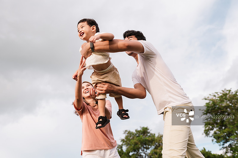 亚洲家庭一起享受户外活动。父母将他们快乐的儿子举到空中，欢笑着增进感情，捕捉自然中家庭时刻的幸福、爱与兴奋。图片素材