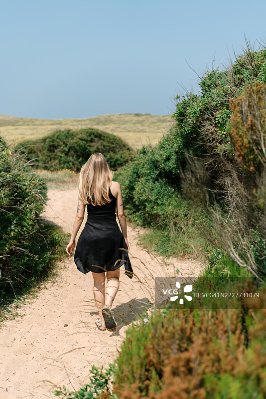 西班牙加泰罗尼亚圣佩雷佩斯卡多尔，女子在植物间的步行道上行走，后视图图片素材