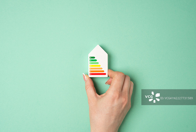 手握房屋模型，展示能源效率评级标准，优化能源使用、节省成本、环境责任和能源保护，乌克兰图片素材