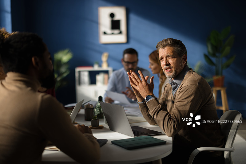 成熟的商人在现代办公室主持团队会议图片素材