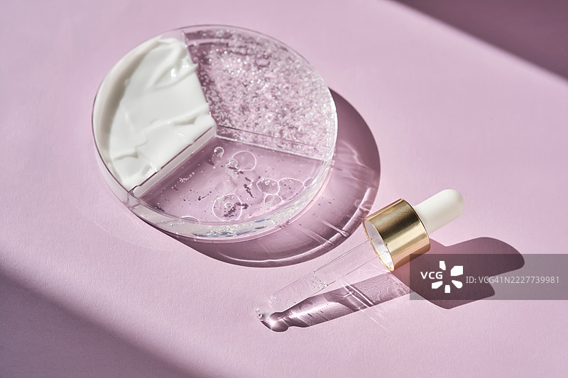 一个三分区的培养皿，上面放着美容护肤产品和一个移液管，背景为紫色。图片素材