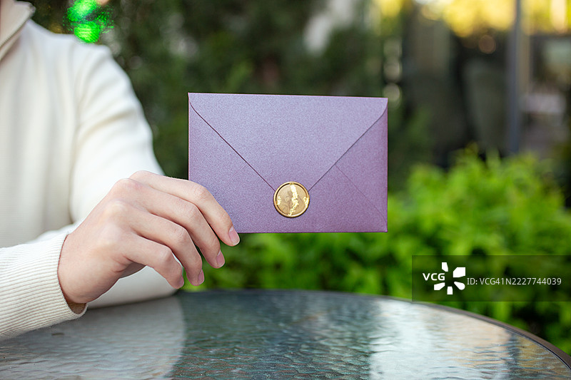 匿名男子手持梅子色的节日证书礼物。图片素材