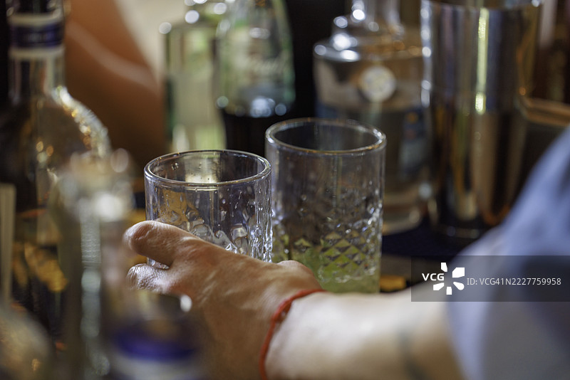 调酒师在繁忙的酒吧里伸手拿鸡尾酒杯图片素材