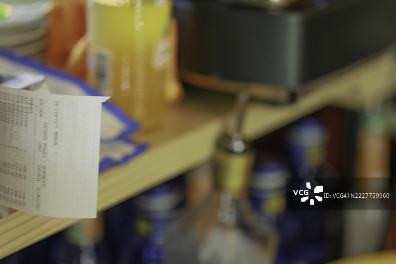 酒吧环境中瓶子架旁的打印收据图片素材