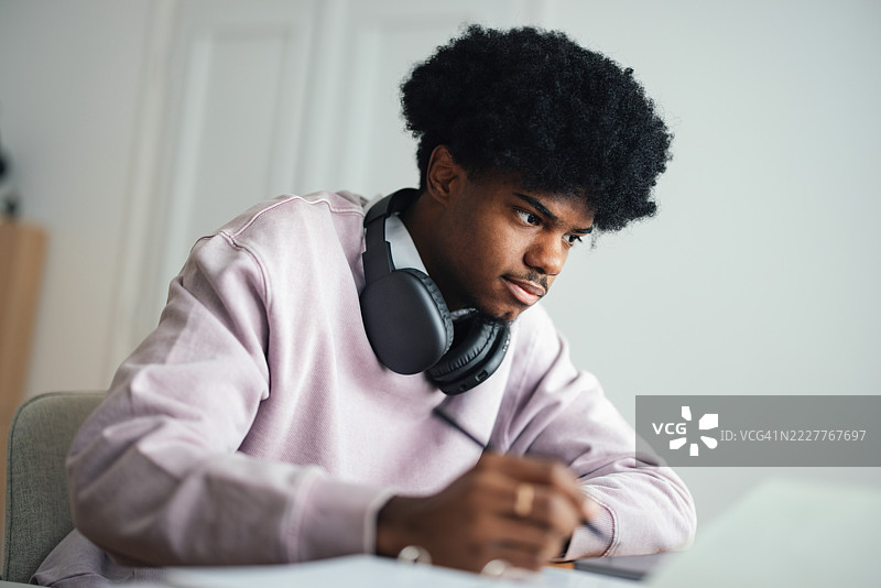 在轻松的环境中，戴着耳机的青少年在家学习图片素材