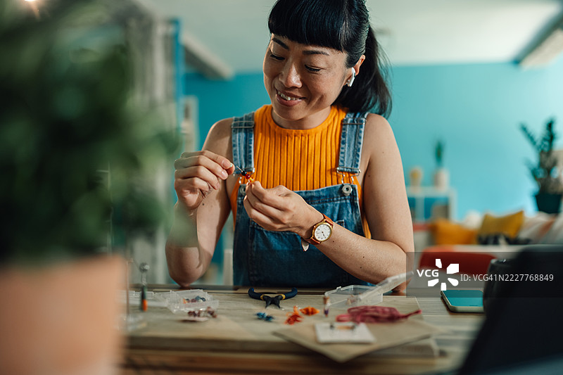 年轻的女工匠在家制作手工珠宝图片素材