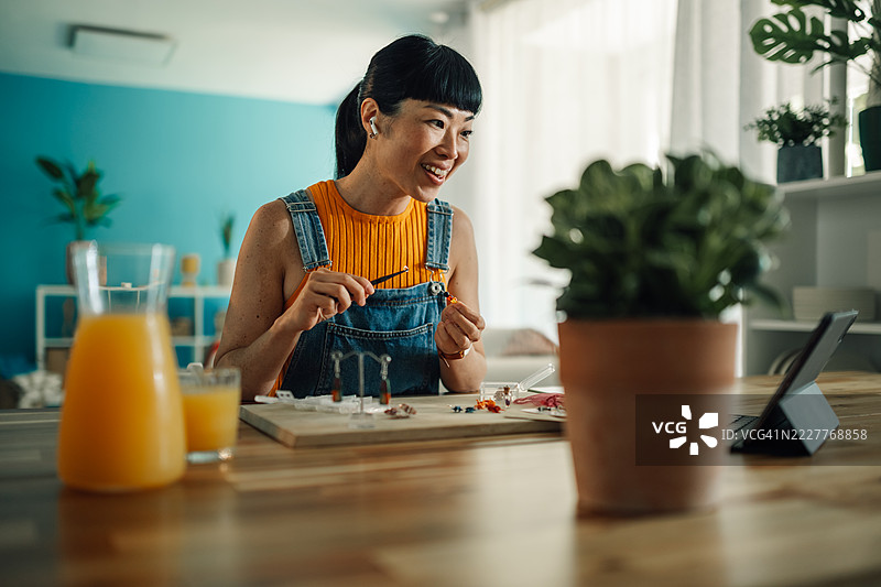 珠宝设计师在家中视频通话时制作手工耳环图片素材