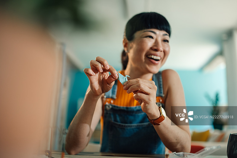 年轻女性在家微笑着折纸图片素材