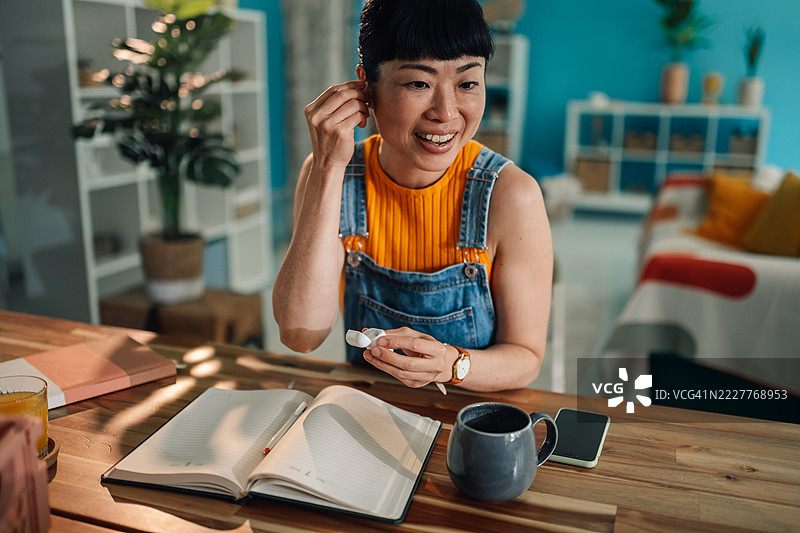 亚洲自由职业者在家工作时戴上耳机图片素材