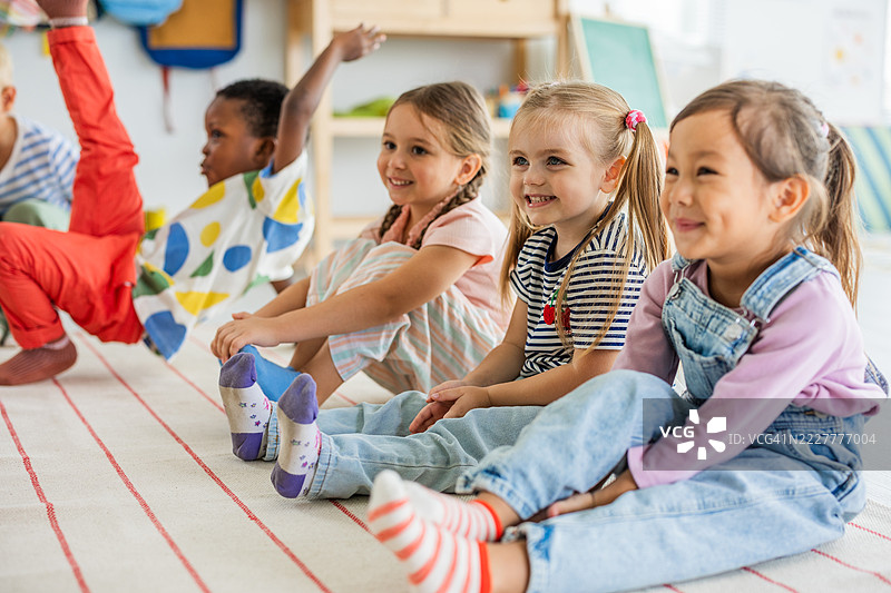 快乐的孩子们坐在幼儿园的地板上图片素材