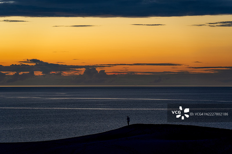 鸟取沙丘沐浴在落日余晖中，孤独的剪影图片素材