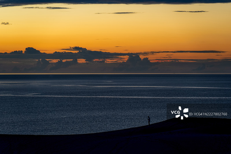 鸟取沙丘沐浴在落日余晖中，孤独的剪影图片素材