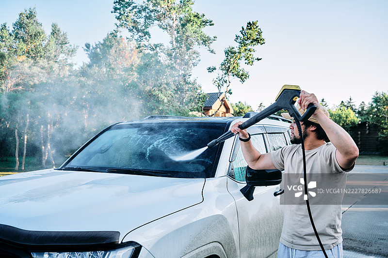男人在户外用高压清洗机洗车。图片素材