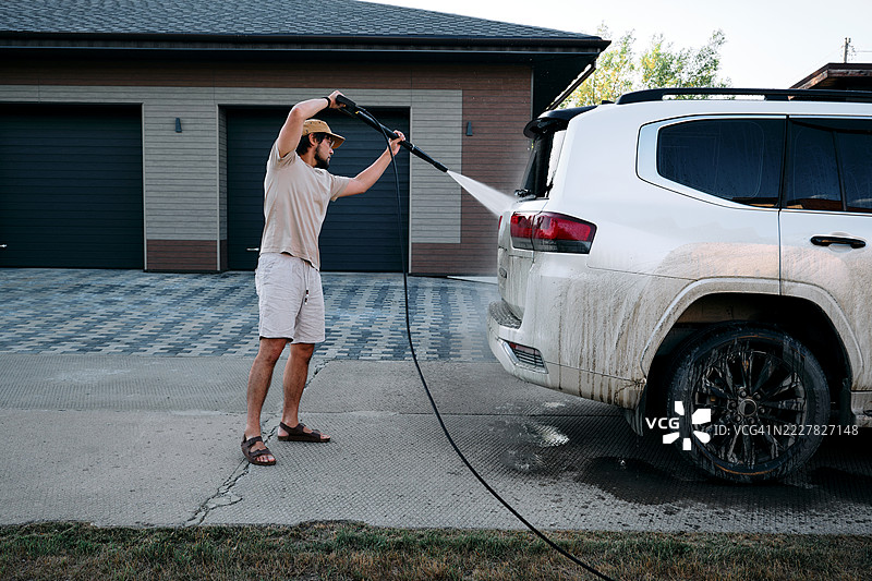 男人在户外用高压清洗机洗车。图片素材