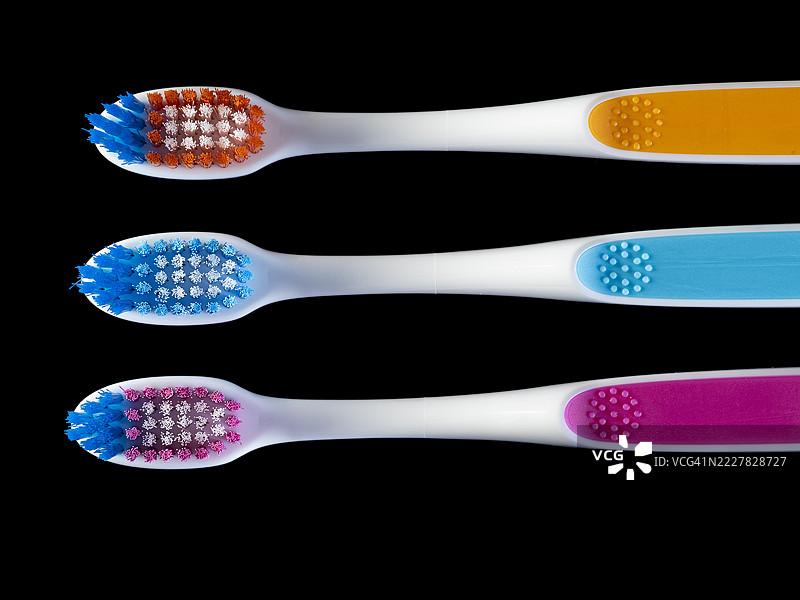 三把牙刷放在黑色背景上。图片素材