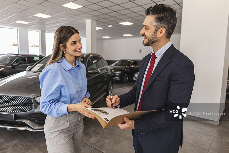 汽车销售员在经销商处帮助客户签署合同图片素材