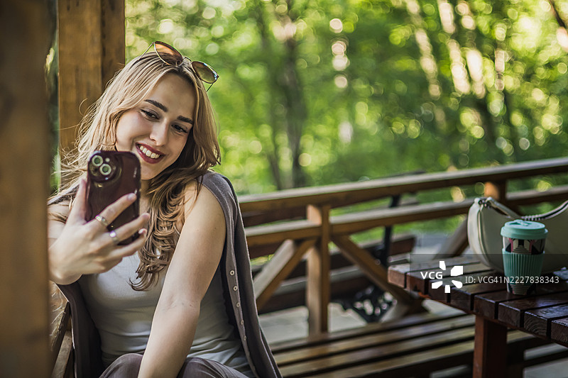 美丽、微笑的年轻女性在公园自拍。快乐的Z世代网红正在为社交媒体直播。图片素材