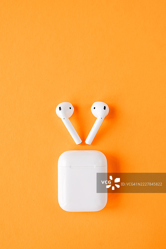 橙色背景上的无线蓝牙耳机图片素材