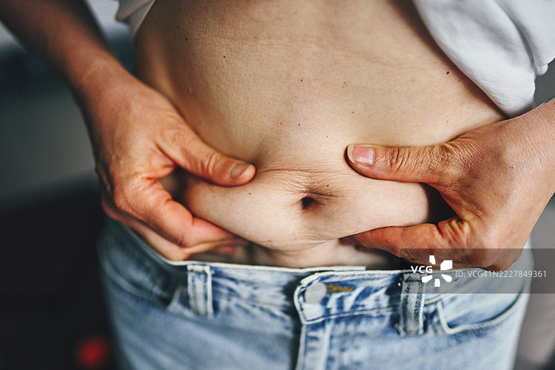 一个人通过捏住腹部皮肤来分析体脂肪图片素材