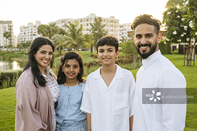 现代沙特家庭的肖像，父母与两个孩子面带微笑，朝镜头看。图片素材
