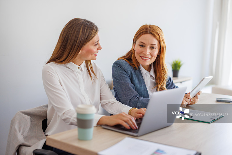 两位女商人在使用笔记本电脑和平板电脑合作项目图片素材