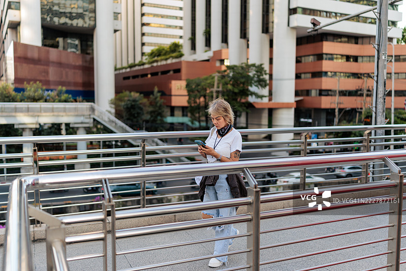 城市中走路的老年女性，正在看手机图片素材