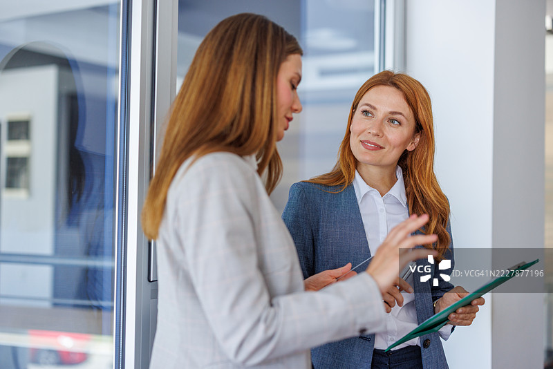两位女商人在办公室走廊讨论工作图片素材