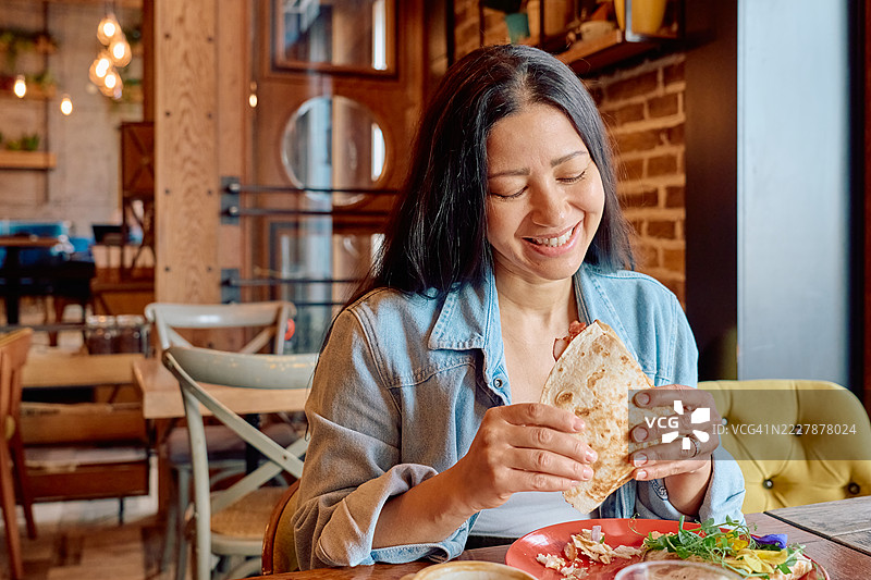 快乐的女人在餐厅里吃皮亚迪纳图片素材